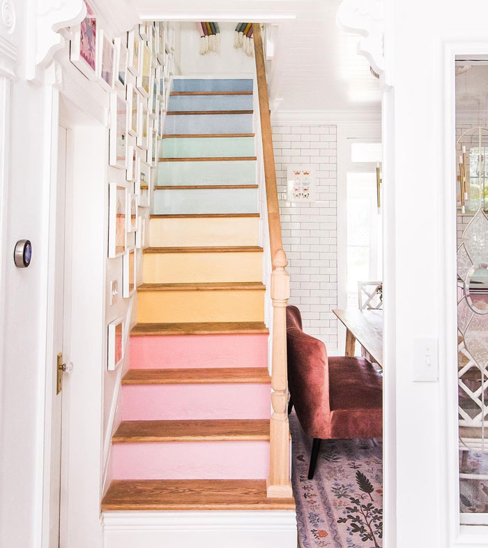 stairs with colorful pastel colored treads and wooden railing