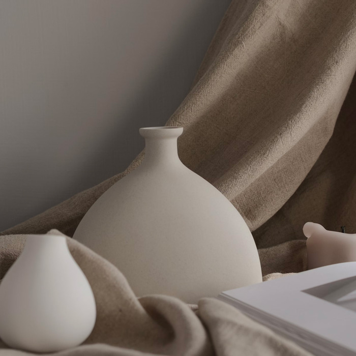 Minimalist decor featuring taupe-toned ceramic vases on a soft taupe fabric backdrop. Minimalist decor featuring taupe-toned ceramic vases on a soft taupe fabric backdrop.