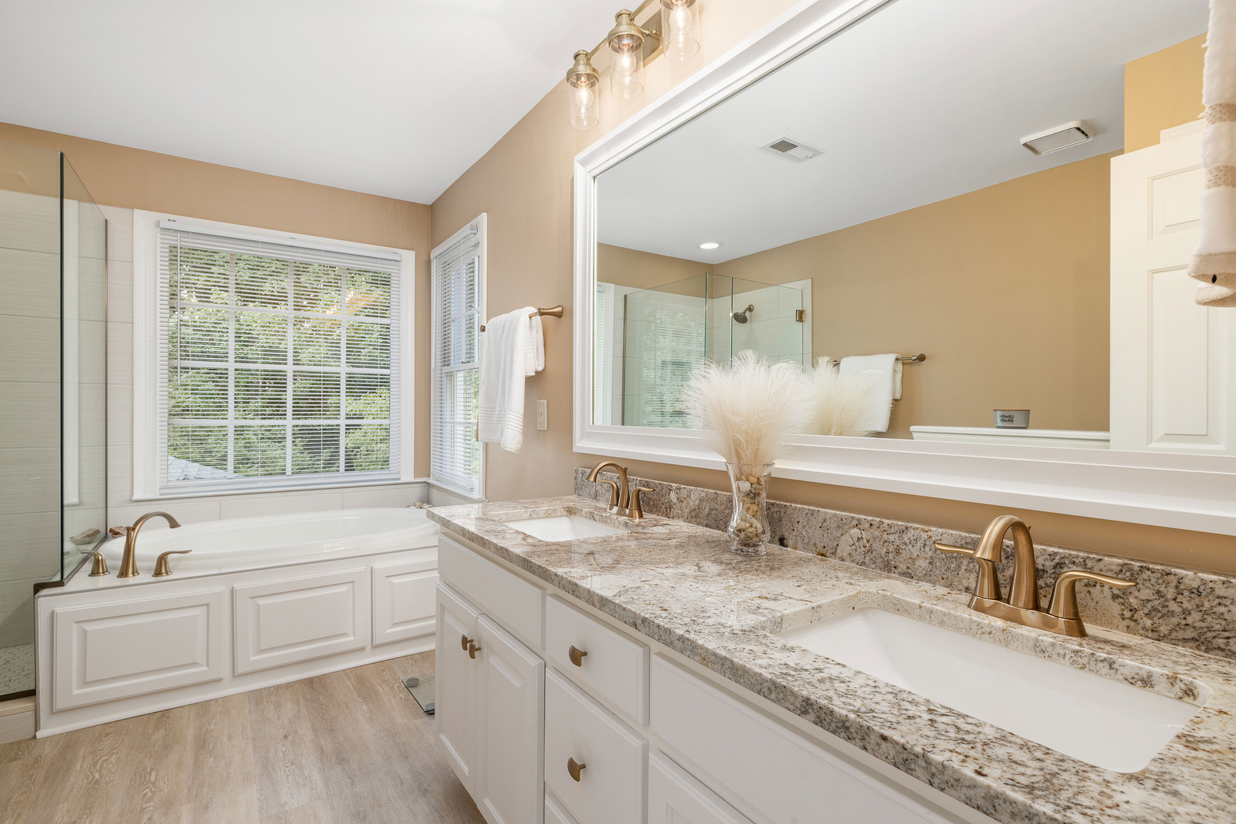 Taupe bathroom with granite countertops, white cabinetry, and a large mirror, showcasing elegant design ideas.