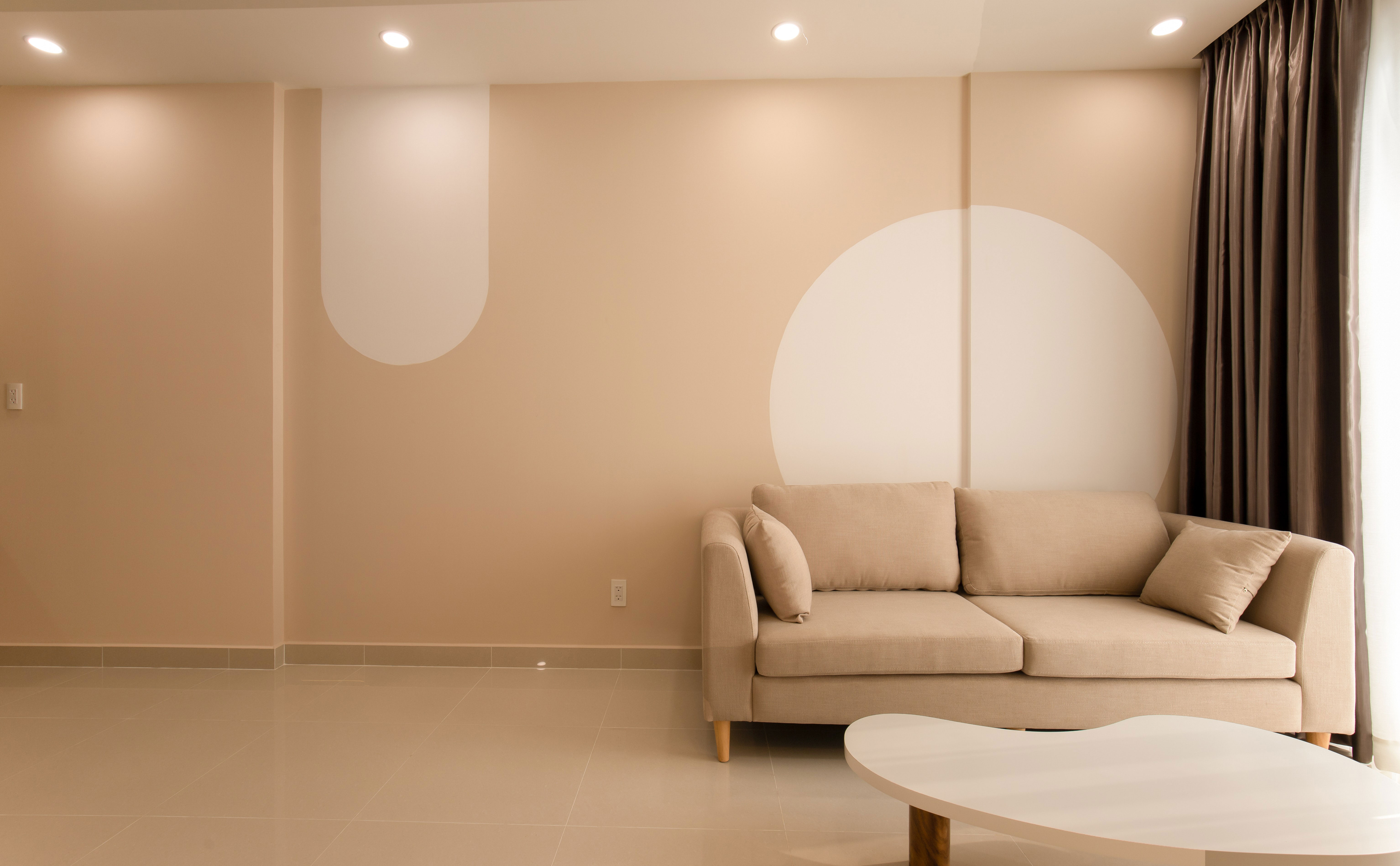 Modern living room with taupe walls, a taupe sofa, and a geometric design, showcasing taupe color ideas.