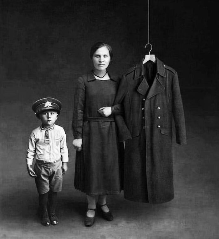 Woman with a child and a large hanging coat in a black and white historical photo vintage portrait.