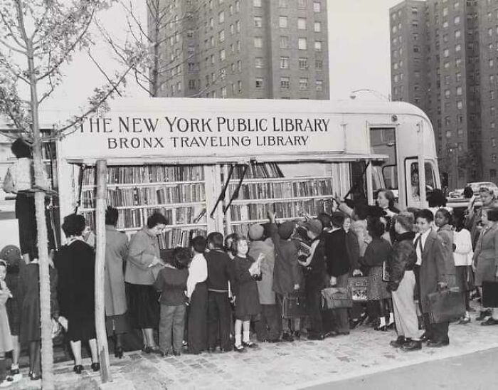 Children lined up outside a historic New York Public Library Bronx traveling library bus in a vintage black and white photo.