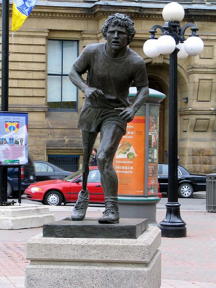 Bronze statue of a runner with a prosthetic leg in an urban setting, symbolizing the coolest person to have ever lived.