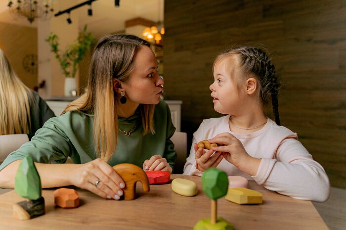 A mother and daughter sharing a moment playing with wooden toys, reflecting unspoken mom code connection.