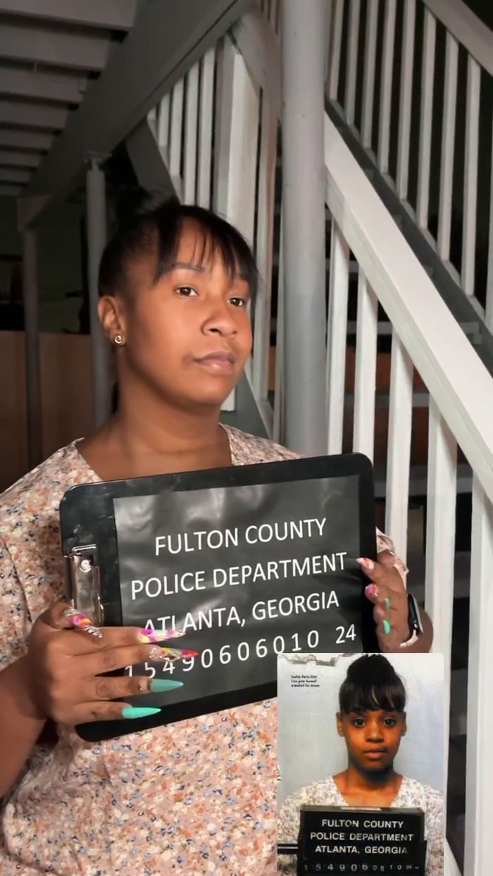 Woman dressed for meme-themed party, holding a sign, in front of stairs.