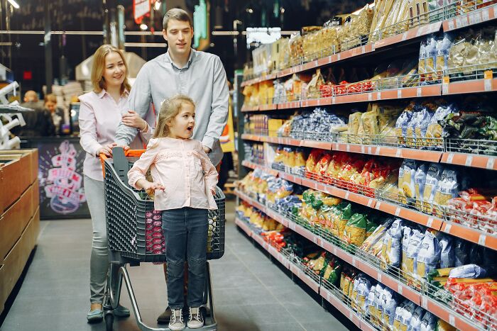 Family shopping together in supermarket aisle, illustrating unspoken mom code and parenting moments connecting mothers online.