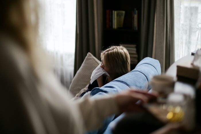 Mother sitting on couch holding tissue, illustrating unspoken mom code and shared maternal experiences.