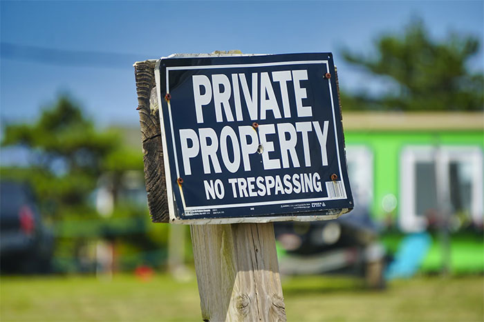 Private property no trespassing sign outdoors reminding visitors what not to do when visiting the US.