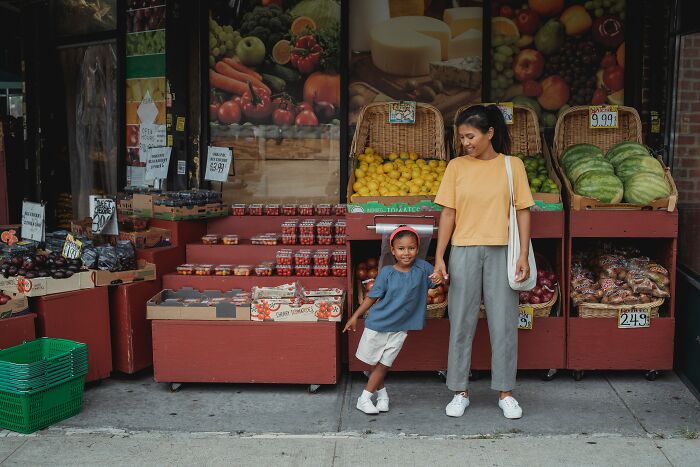 Mother and child holding hands outside a fresh produce market, reflecting unspoken mom code moments.