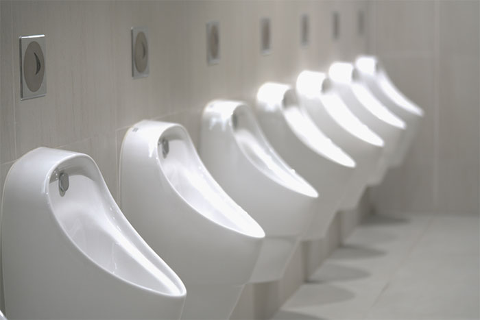 Row of clean white urinals in a public restroom, highlighting what not to do when visiting the US to avoid health risks.