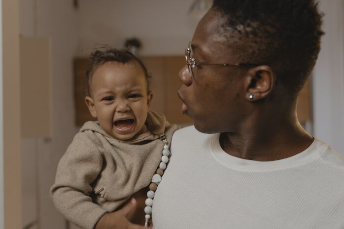 Mother comforting crying baby indoors, illustrating unspoken mom code and maternal care in a home setting.