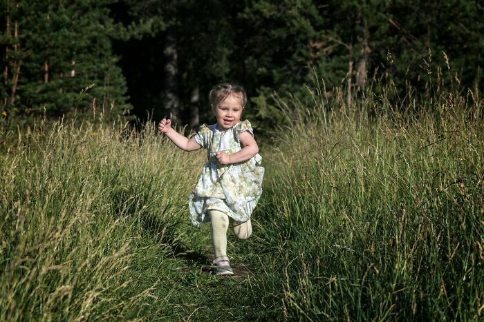 Young child joyfully running down a grassy path in nature, capturing a moment tied to unspoken mom code experiences.