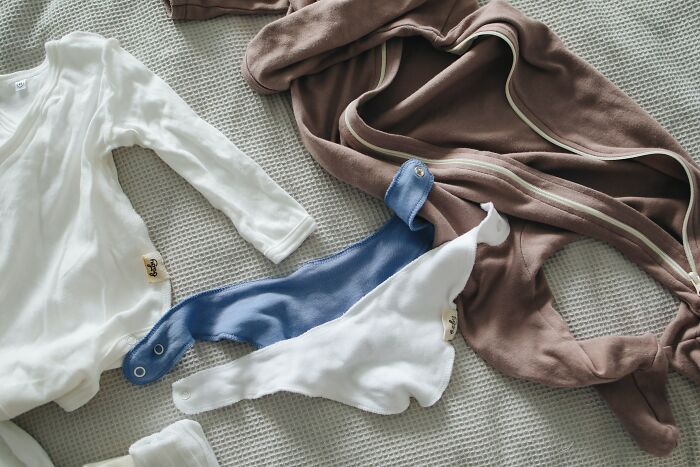 Baby clothes and a brown robe laid out on a textured surface representing unspoken mom code essentials