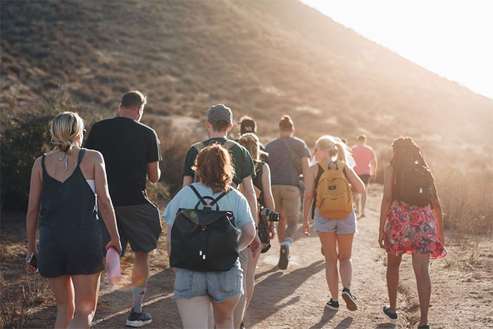 Group of hikers walking on a sunlit trail in nature, illustrating tips on what not to do when visiting the US.