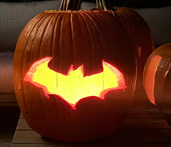 Pumpkin carved with Batman symbol and glowing from inside, linked to Matthew Perry's mysterious Batman-themed posts.