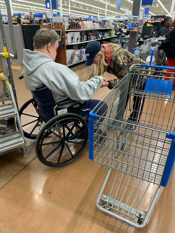 Señora rezando por este hombre para que pueda volver a caminar