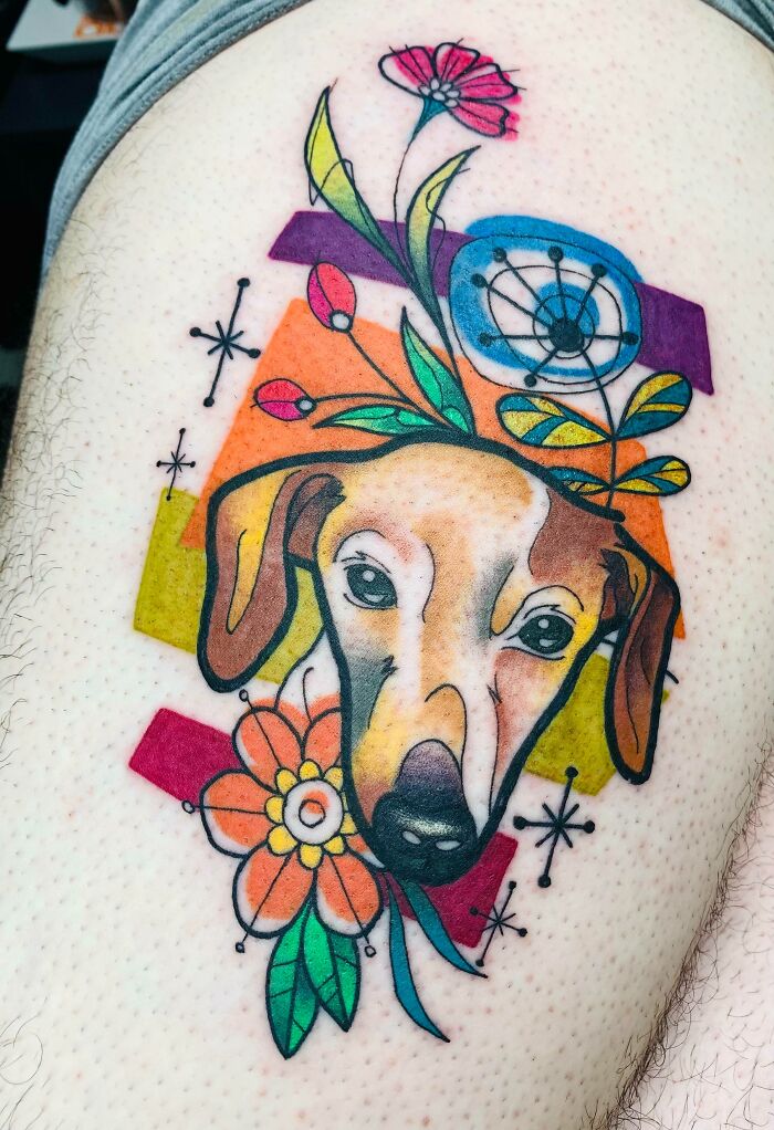 Colorful dog memorial tattoo with flowers and abstract shapes on skin.