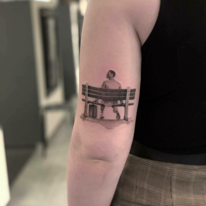 '90s tattoo featuring a person sitting on a bench with a suitcase, capturing the decade's cultural vibe.