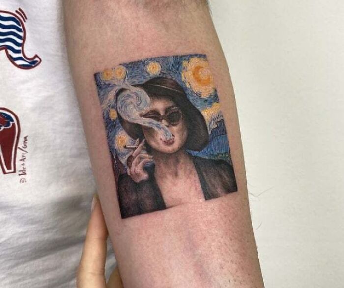 '90s tattoo featuring a surreal image of a woman smoking, framed by a starry night background on a person's arm.