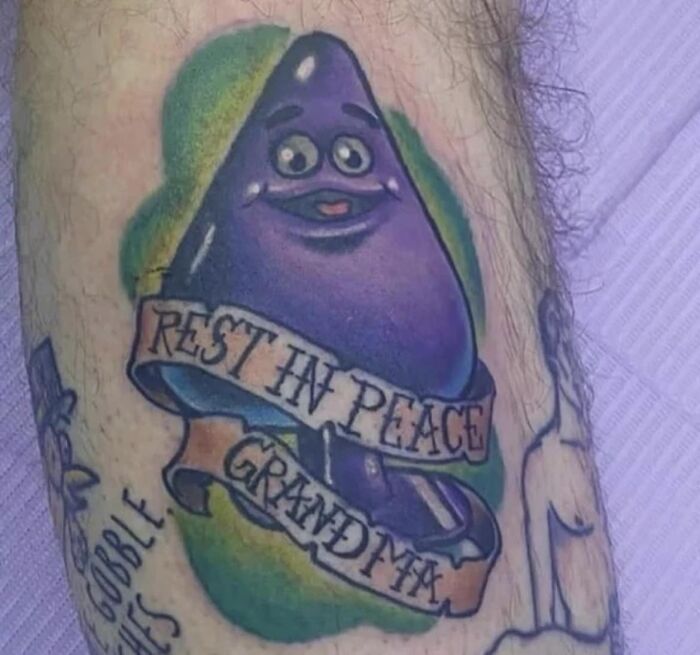Purple cartoon face tattoo with "Rest in Peace Grandma" banner, representing one of the worst tattoo designs.