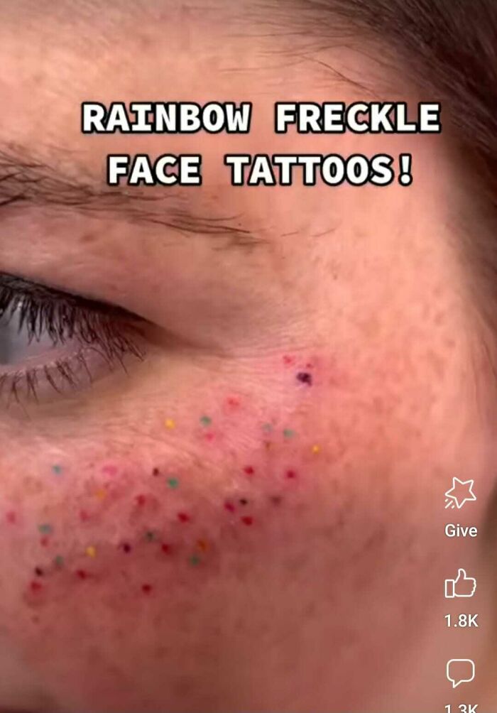 Rainbow freckle face tattoos close-up, featuring colorful ink dots on cheek.