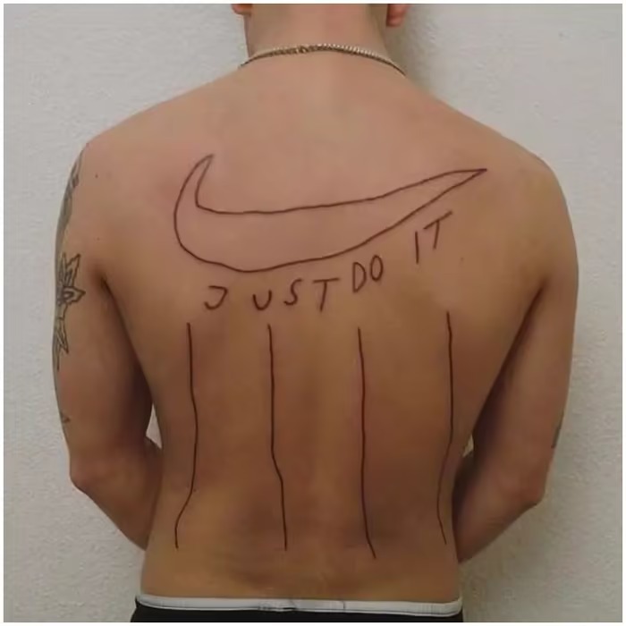 Back tattoo with an irregular Nike logo and "Just Do It" text, considered one of the worst tattoo designs.