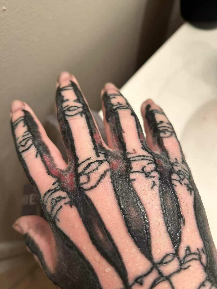 Close-up of a hand with skeleton-themed tattoo.