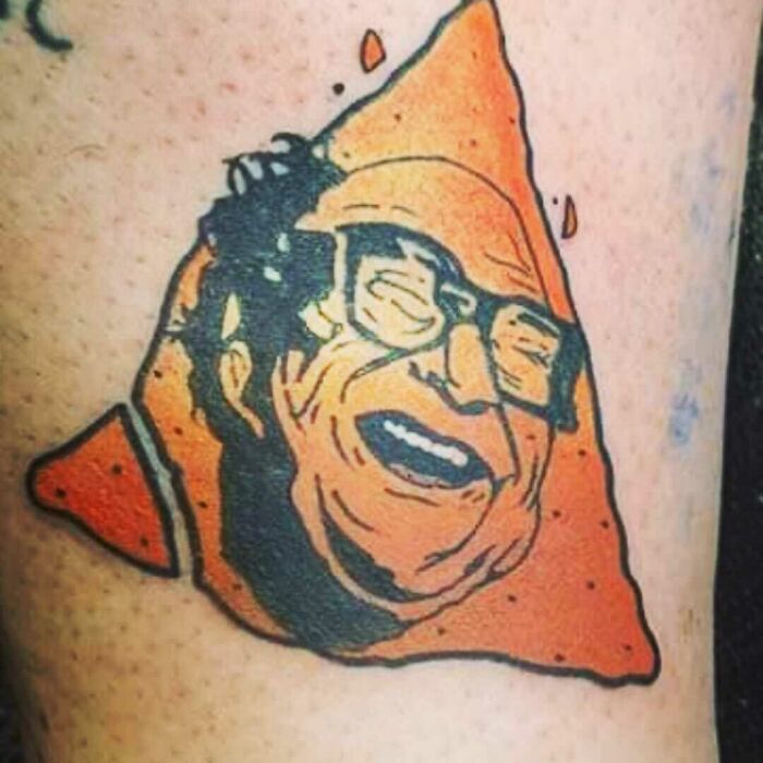 Unusual tattoo featuring a grinning face on an orange triangle shape, illustrating one of the worst tattoo choices.