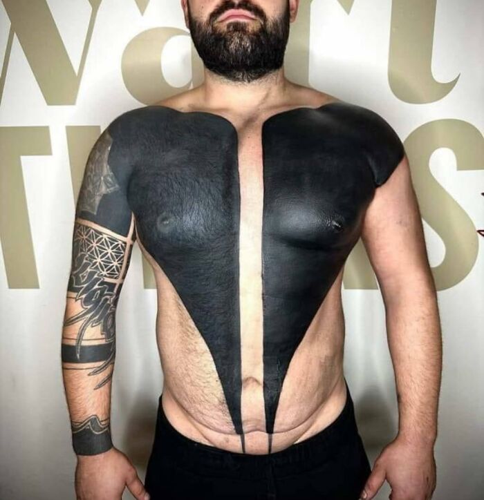 Man with large black chest tattoo resembling open shirt, showcasing bad tattoo choice.