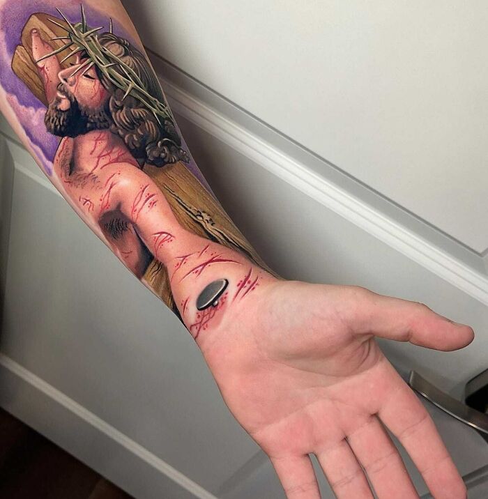 Forearm with detailed religious tattoo design, depicting a significant biblical scene and intricate details.