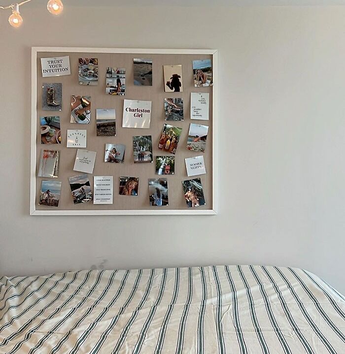 Wall-mounted pinboard with photos and notes above a striped bed, showing creative bedroom wall decor ideas.