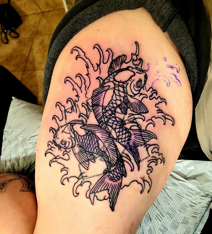 Fixed tattoo of koi fish with detailed lines on skin.