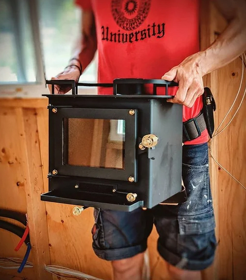Man lifting small wood-burning stove