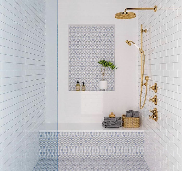 Blue and white bathroom featuring mosaic and penny tiles on walls and flooring with gold shower fixtures.