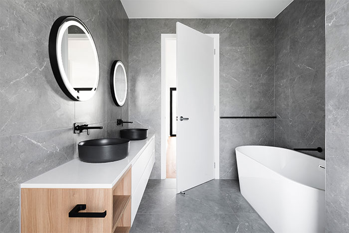 Modern bathroom featuring stylish wall and flooring tile design with white ceramic sink and black fixtures