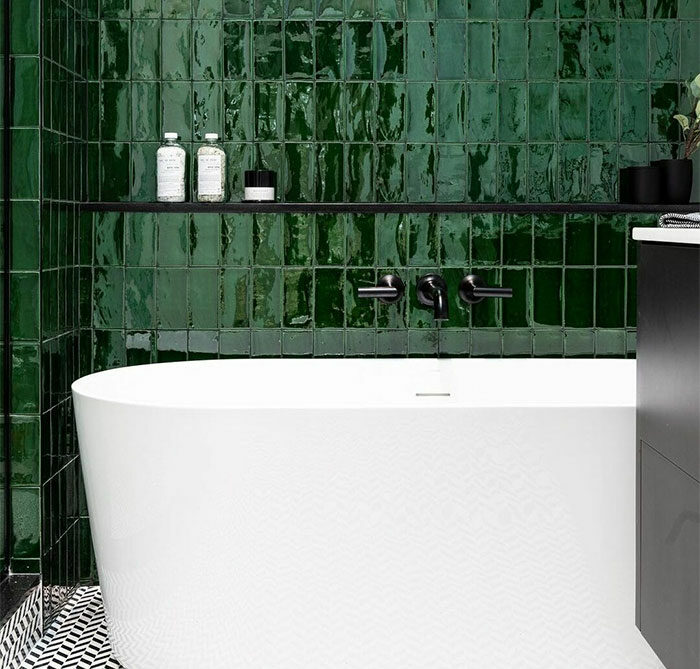 Bathroom with green glass tiles on the walls and a modern freestanding white bathtub, showcasing beautiful bathroom tile design ideas.