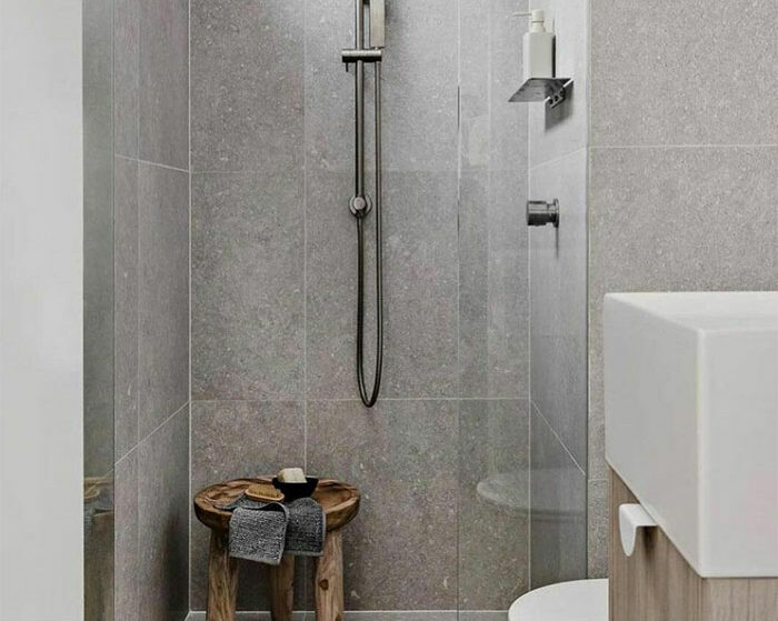 Bathroom with gray limestone tiled walls and flooring showcasing beautiful bathroom tile design ideas.