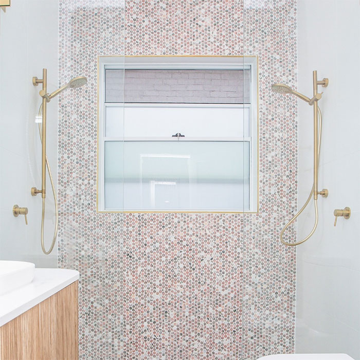 Bathroom with colorful hexagon mosaic tile design on shower wall featuring modern brass fixtures and white accents.