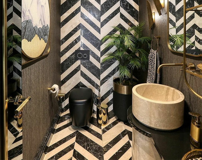 Bathroom featuring black and white chevron tile design on walls and flooring with a modern sink and toilet.