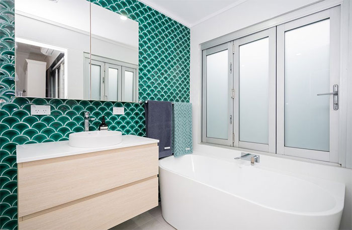 Bathroom with green fish-scale tile wall and modern sink showcasing beautiful bathroom tile design ideas.
