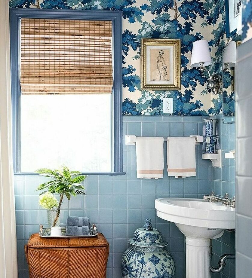 Bathroom with blue tiles on walls, floral wallpaper, white sink, and woven wicker basket for decor and storage.