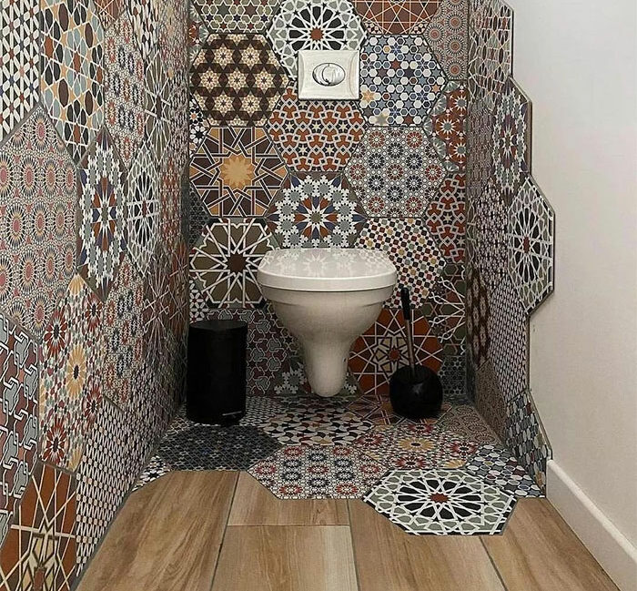 Modern Moroccan style bathroom tile design with hexagonal patterned walls and flooring around a white wall-mounted toilet.