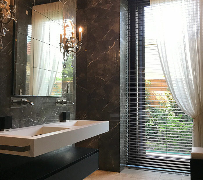 Modern bathroom with two white ceramic sinks, gray stainless steel faucets, and beautiful tile design on walls and floor.