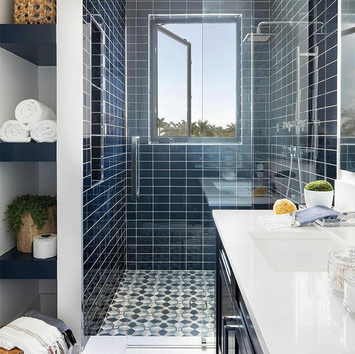 Bathroom featuring different blue tile design ideas on walls and patterned flooring with a modern glass shower enclosure.