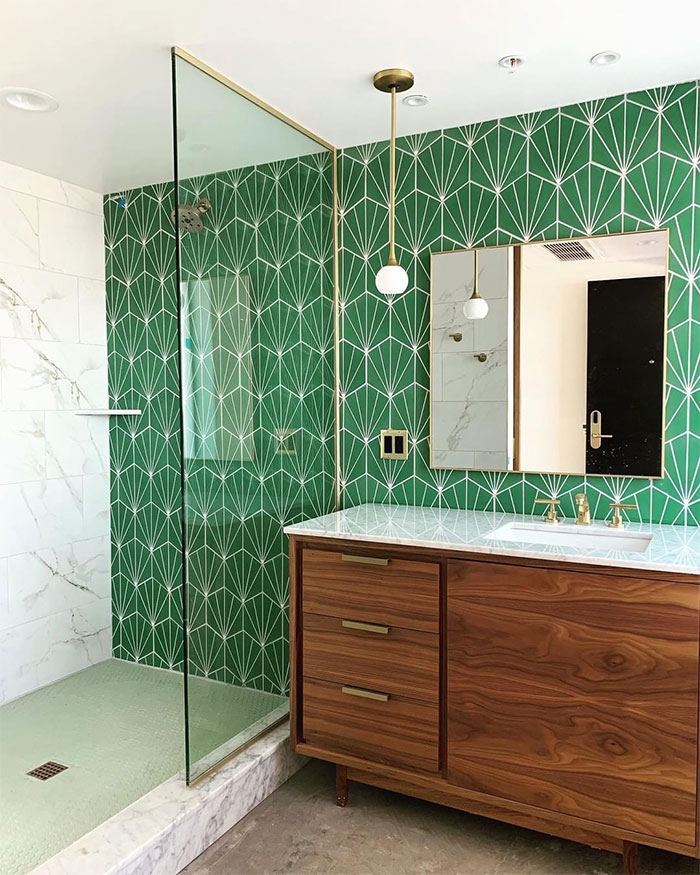 Bathroom featuring green tropical bathroom tile design on walls with wooden vanity and modern fixtures.