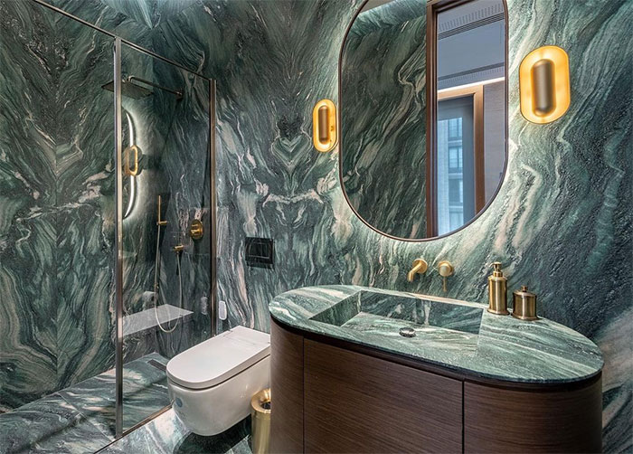 Bathroom with green marble tile design on walls and floor, featuring matching sink and modern toilet fixtures.