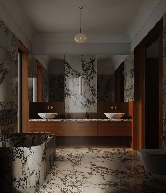 Dark bathroom featuring beautiful bathroom tile design with patterned marble flooring and walls and wooden cabinets.