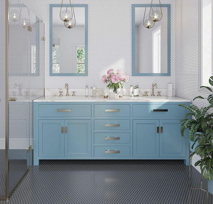 Bathroom with black and white penny tile design on walls and flooring, featuring a blue double sink vanity and mirrors.