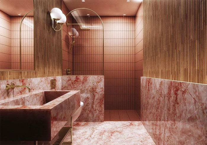 Beautiful bathroom featuring pink marble tiles on walls and flooring with a matching marble sink and brass fixtures.