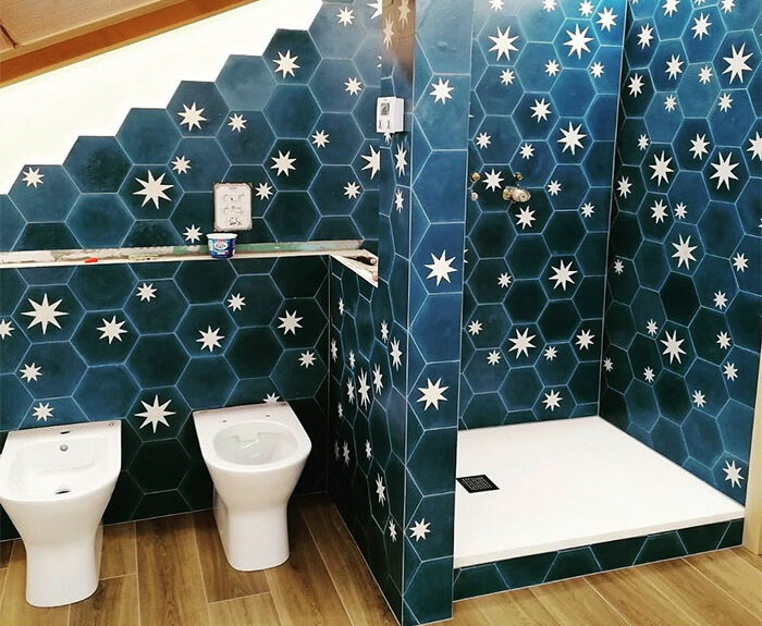 Bathroom featuring blue hexagon bathroom tile design with white star patterns on walls surrounding shower and fixtures.